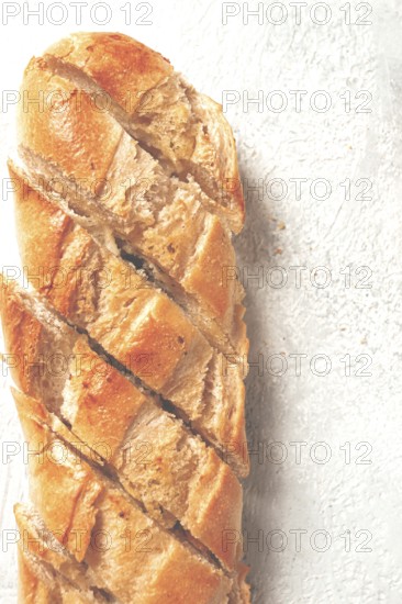 Garlic bread, baguette with garlic butter and herbs, on a light table, top view