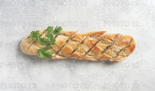 Garlic bread, baguette with garlic butter and herbs, on a light table, top view