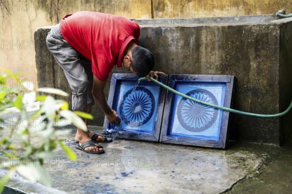 Employee of the Assam Khadi and Village Industries Board cleaning Ashoka Stambh screen printing block in a manufacturing unit of Indian National Flag, ahead of 79th Independence Day, in Guwahati, India on 11 August 2025