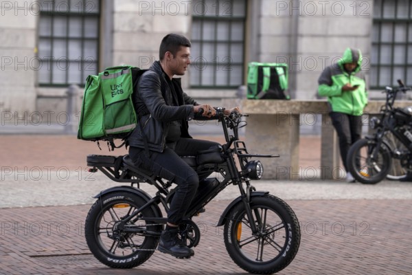 Bicycle traffic in Groningen, Uber Eats, courier driver with e-bike in moped style, fatbike, Netherlands
