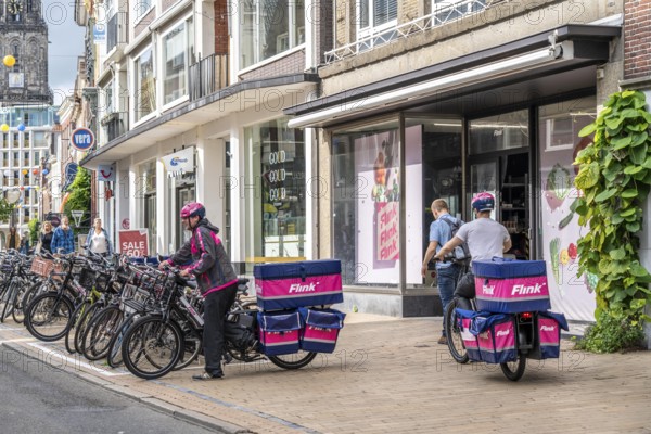 Bicycle traffic in the city centre of Groningen, old town, branch of the food delivery service Flink, Netherlands