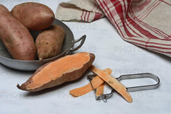 Sweet potatoes in skin and potato peeler, Ipomoea batatas