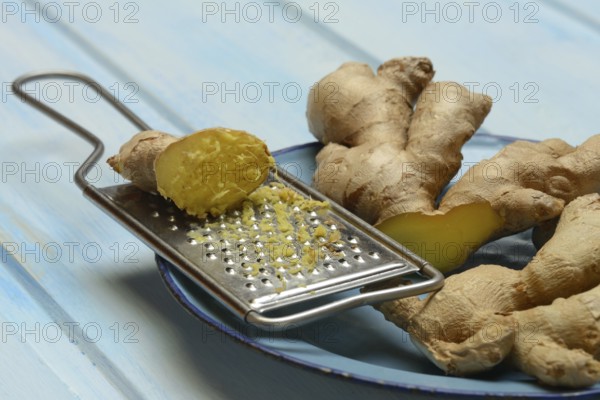 Ginger tubers and lemongrass on plate, grater with ginger pieces