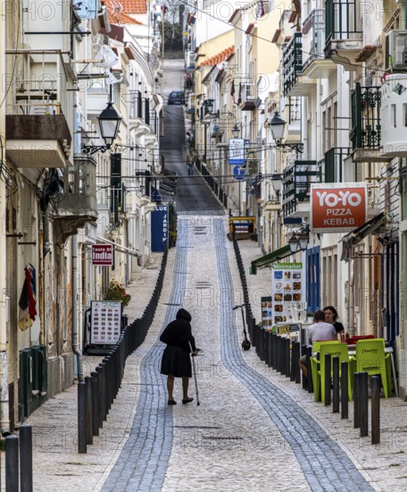 Sticker-covered sign with bicycles and surfboards, Nazaré, Portugal
