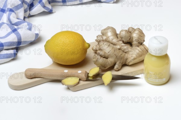 Ginger root and lemon on cutting board with knife, ginger shot