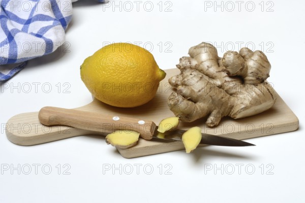 Ginger root and lemon on kitchen board with knife, ginger slices, Zingiber officinale