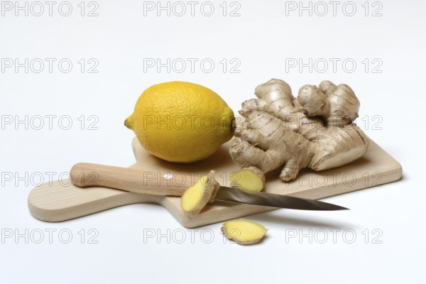 Ginger root and lemon on cutting board with knife, ginger slices, Zingiber officinale