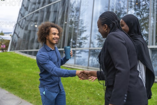 Diverse business professionals meeting and exchanging a friendly handshake outdoors in a modern urban environment, symbolizing collaboration, partnership, and professional networking