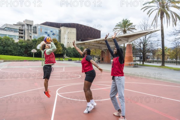 Group of diverse young athletes enjoying a spirited game of basketball outdoors, actively involved in teamwork and healthy competition on an urban court