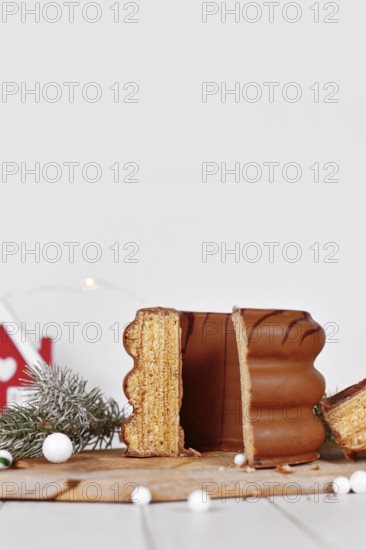 Cut open cake called 'Baumkuchen', a German layered cake glazed with chocolate, surrounded by seasonal decoration