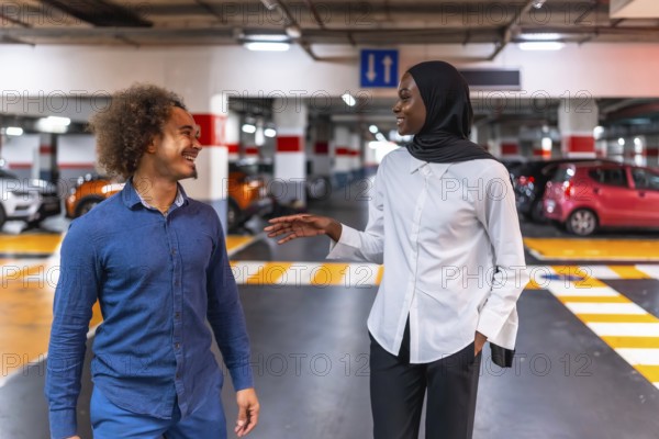 Diverse young couple smiling and talking, sharing a happy moment with engaging conversation in a modern underground parking garage environment, depicting friendship and urban interaction