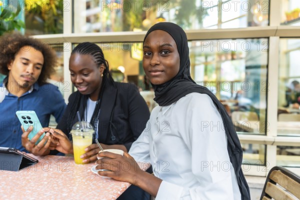 Diverse group of young friends at a cafe laughing and sharing content on a smartphone, enjoying coffee, casual conversation and modern social connection in a multicultural urban setting