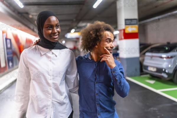 Diverse young couple happily walking arm in arm through a modern underground parking garage, sharing a moment of connection and togetherness in an urban environment