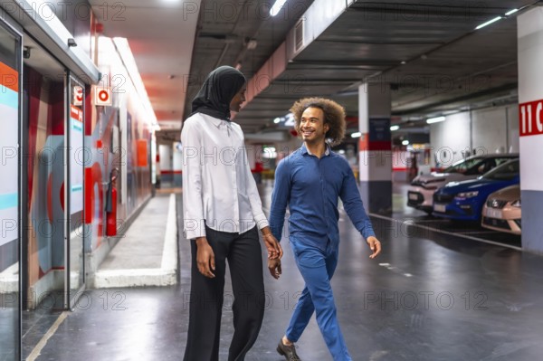Diverse young couple walking hand in hand through an underground parking garage, sharing a loving moment and smiling, representing connection and modern urban life