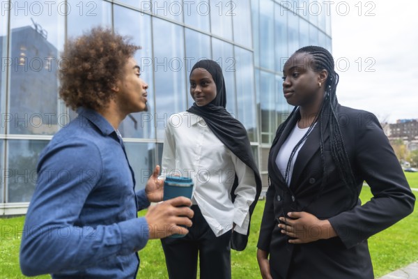 Diverse business professionals standing outdoors, engaging in an informal discussion during a break, demonstrating collaboration and teamwork in a modern urban environment