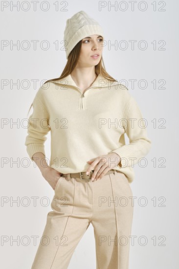 A woman poses confidently in a cozy cream sweater and stylish beige pants, perfect for a casual outing