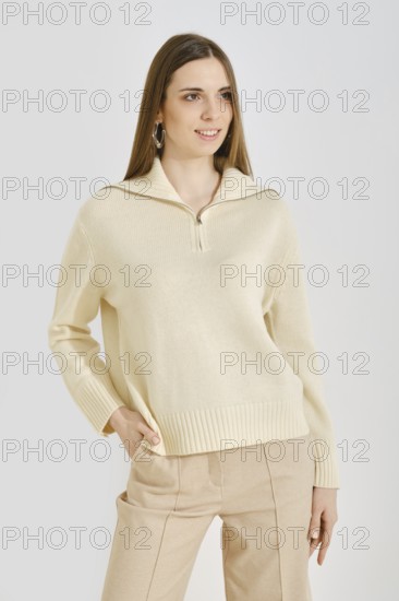 A young woman poses in a trendy cream sweater with a zip collar paired with beige pants. This outfit focuses on convenience and practicality, ideal for casual outings or daily activities