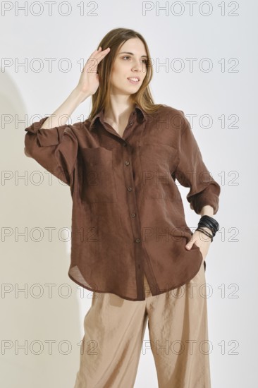 A woman showcases a stylish outfit with a brown button-up shirt and light beige pants, perfect for a casual afternoon