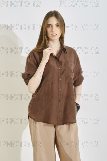 A woman stands confidently, wearing a trendy brown shirt and light-colored pants, perfect for casual outings. The outfit showcases a blend of comfort and style, ideal for various daily activities