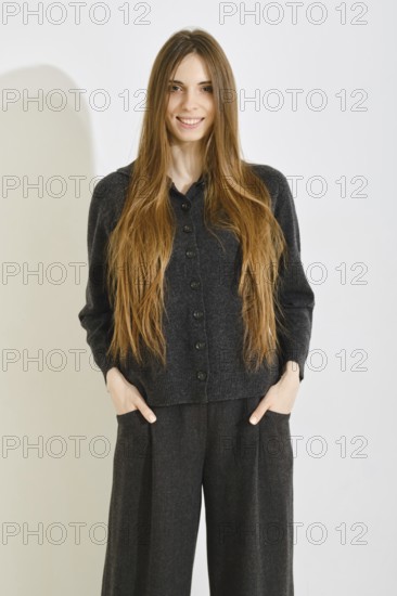 Smiling woman poses in a comfortable black outfit featuring a soft button-up top and loose pants on bright background