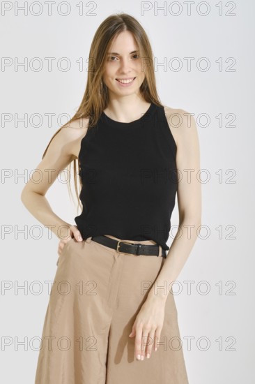 A young woman showcases a trendy black sleeveless top paired with wide-legged beige pants. This look highlights practicality and comfort, ideal for casual outings or daily activities