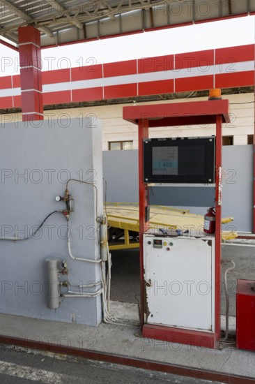 Red gas pump with screen and cables in front of a grey wall, gas filling station, Sewan, Gegharkunik province, Armenia
