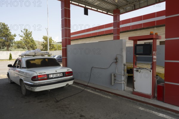 White car connected to red gas station pump under a canopy, gas filling station, Sewan, Gegharkunik province, Armenia