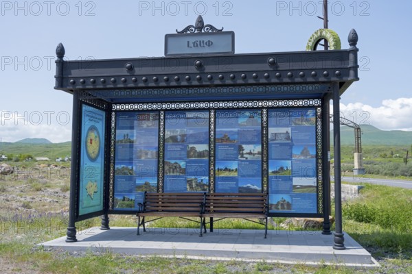 Bus stop with information posters surrounded by rural landscape under blue sky, bus stop at Lake Sevan, Gegharkunik Province, Armenia