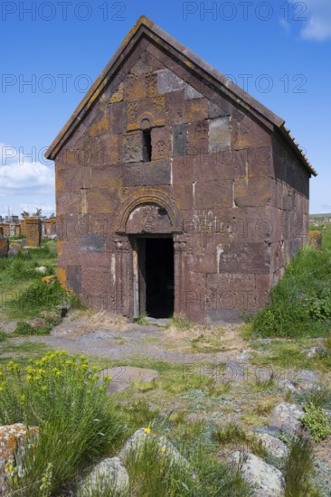 Old Armenian stone church with vaulted entrance surrounded by green landscape, Noratus cemetery, Noradus, Gegharkunik province, Armenia
