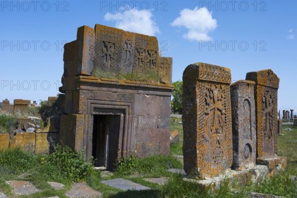Decorated mausoleum and tombstones with chisels on a green field, crossstones, khachkars, world's largest khachkar field, Noratus cemetery, Noradus, Gegharkunik province, Armenia