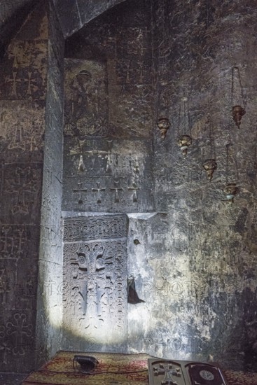 Dark church interior with carved cross and ornaments on the wall illuminated by soft light, Hajravank Monastery, Hayravank, Lake Sevan, Gegharkunik Province, Armenia