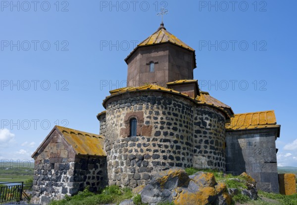 Historic stone church with a round tower in a rural setting under blue sky, Hajravank Monastery, Hayravank, Lake Sevan, Gegharkunik Province, Armenia