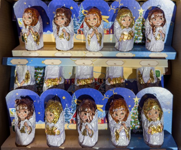 Chocolate Christmas angel in musical instruments printed on colorful staniol paper on a retail shelf, Germany