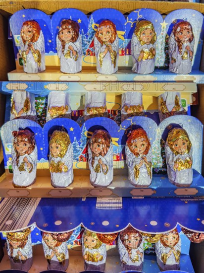 Chocolate Christmas angel in musical instruments printed on colorful staniol paper on a retail shelf, Germany