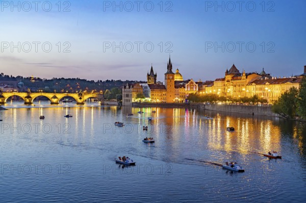 Vltava embankment with Old Town Water Tower, Novotný Bridge and Charles Bridge at dusk, Prague, Czech Republic