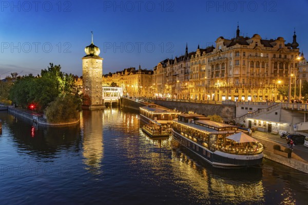 Hotel boats on the banks of the Vltava river and Sitkov water tower at dusk, Prague, Czech Republic
