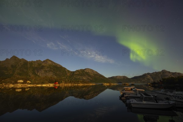 Northern lights are reflected in the fjord in Norway. Aurora Borealis over Festvåg near Bodø, Nordland, Norway