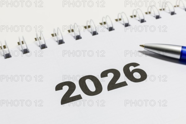 Ring book calendar for the year 2026 with ballpoint pen on white background