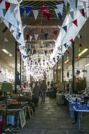 Market stalls with bunting flags inside historic Shambles market hall building, Devizes, Wiltshire, England, UK