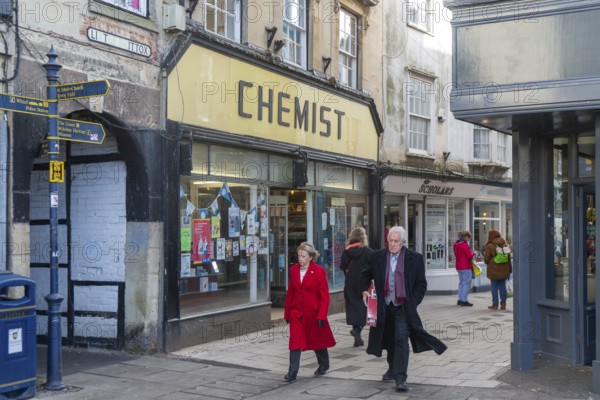 Shops and shoppers in Little Brittox street, Devizes, Wiltshire, England, UK traditional Chemist shop shopfront