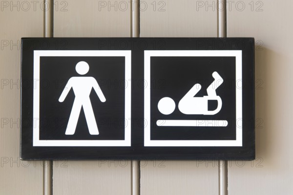 Pictogram sign for nappy changing facility in male bathroom toilets, UK