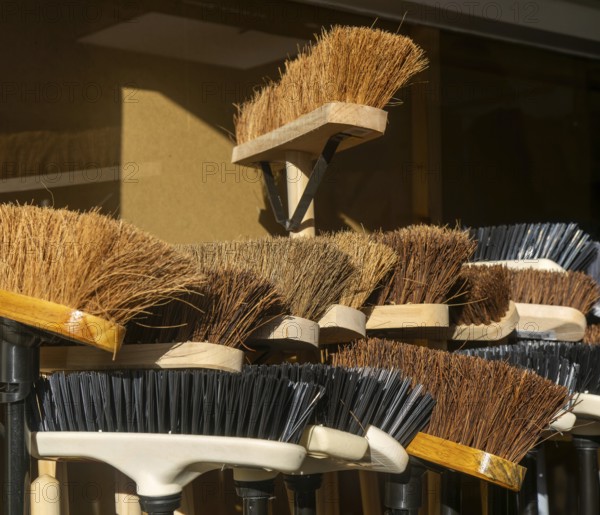 Display of bristled heads of broom brushes outside hardware shop, UK