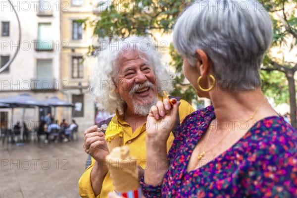 Senior couple laughing and sharing ice cream on a sunny summer date in a lively european city square, enjoying casual outdoor fun, togetherness and relaxed vacation vibes