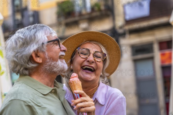Senior couple laughing and enjoying a refreshing ice cream cone together during a relaxing summer day in a charming european city street, celebrating love and active retirement