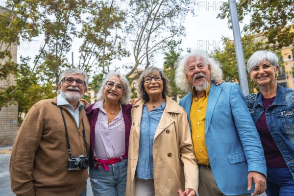 Group of five happy senior friends standing together, smiling and embracing outdoors while traveling in a city, sharing a special bond and active retirement lifestyle