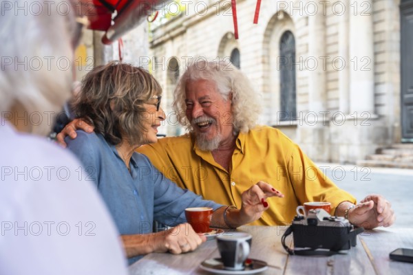 Senior friends sharing a moment of joy and laughter while having coffee at an outdoor cafe, embodying happiness, friendship, and a vibrant active senior lifestyle