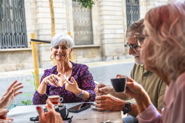 Mature adults gathering socially at an outdoor cafe, enjoying coffee and engaging in lively conversation, representing retirement, friendship, and a happy lifestyle