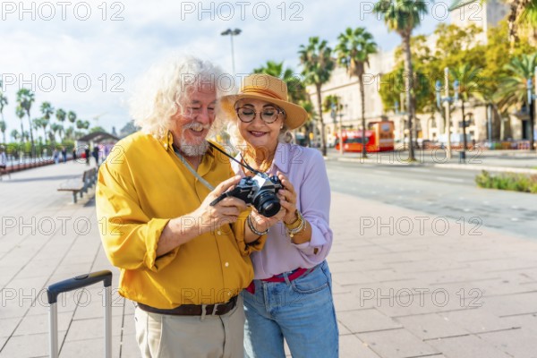 Happy senior couple exploring a sunny european city, smiling as they review photos on a vintage camera, enjoying retirement travel, sightseeing and making memories together