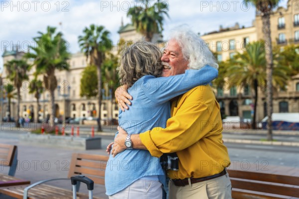 Enthusiastic senior couple embracing each other with joy and affection in a city setting, enjoying travel and leisure together on an urban street with palm trees