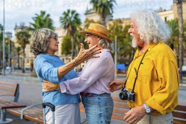 Senior friends embrace in an urban square, joyful reunion while traveling overseas, smiling and celebrating friendship, leisure sightseeing and shared happy moments